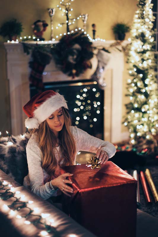 Woman putting a bow on a present for Christmas.